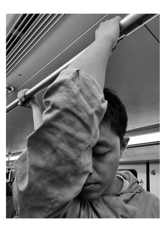 一个年轻人坐在火车或地铁上 抱着他的头