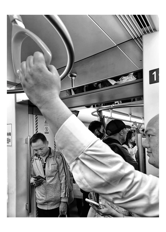 一张黑白照片 一个男子在地铁或地铁列车上举起他的手。