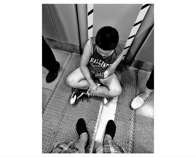 一个小男孩坐在楼梯上 正看着一个小人在厕所里坐着。