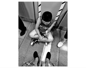 一个小男孩坐在楼梯上 正看着一个小人在厕所里坐着。