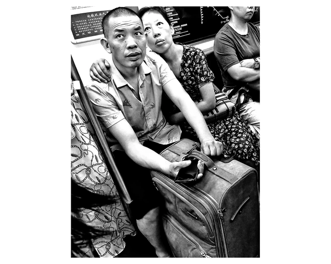 一张黑白照片 一对年轻男女坐在火车上 带着行李。