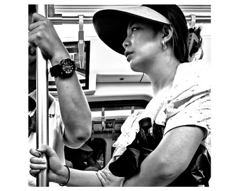 一张黑白照片 一位女士戴着帽子乘坐公交车 手里拿着一把伞。