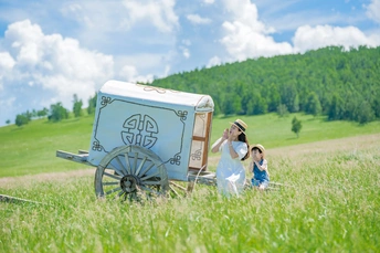 一个小女孩坐在一辆马车上 马车由一个女人和一个小孩拉着