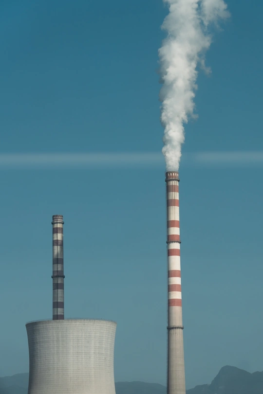 一个工业工厂或工厂 冷却塔排放着白烟 直冲蓝天。