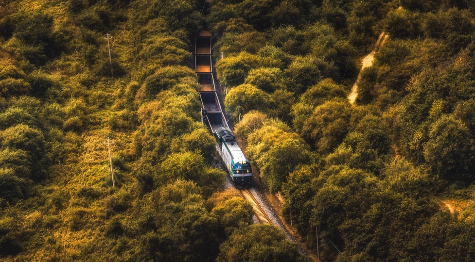 火车穿过一片绿色的山丘和树木的森林的俯视图