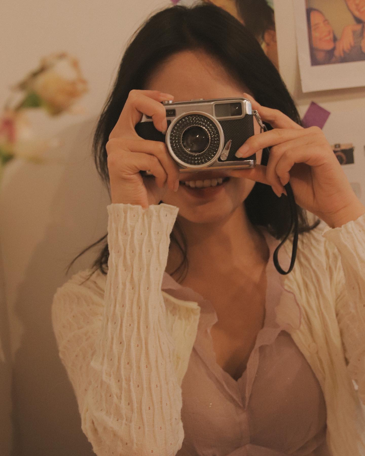 一个年轻的女人拿着相机在镜子里给自己拍照