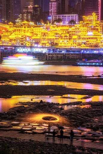 一群人站在水体旁 背景是一座城市