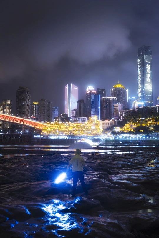 一个人站在水中 夜晚背景是一座城市