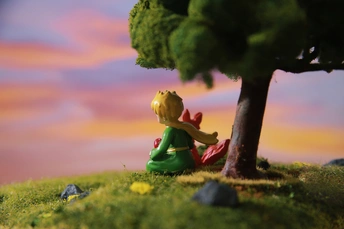 一个小女孩坐在树下的一个 figurine