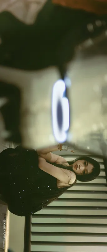 一位穿着连衣裙的女人正在镜子前拍照 拍自己的倒影。