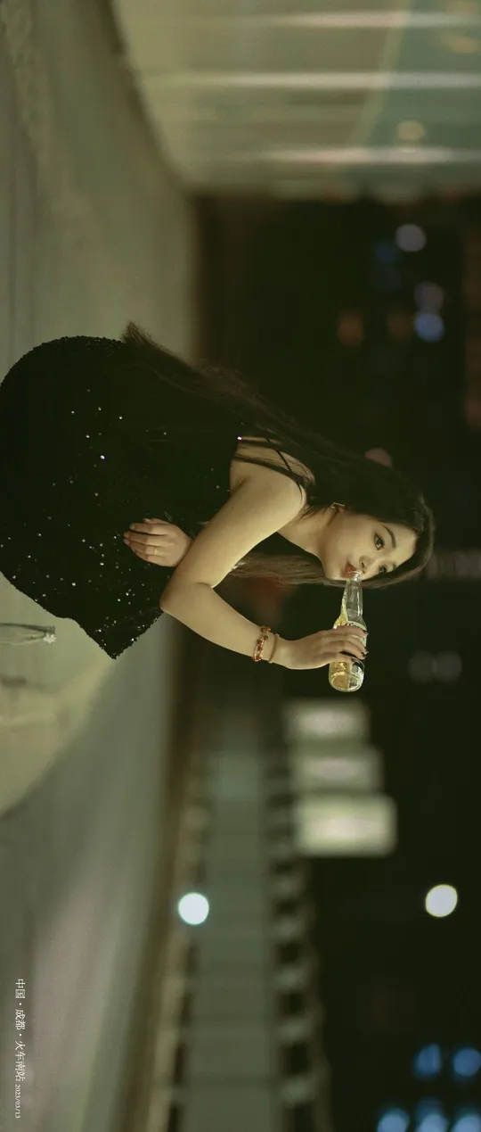 一位穿着黑色连衣裙的女士拿着一瓶水