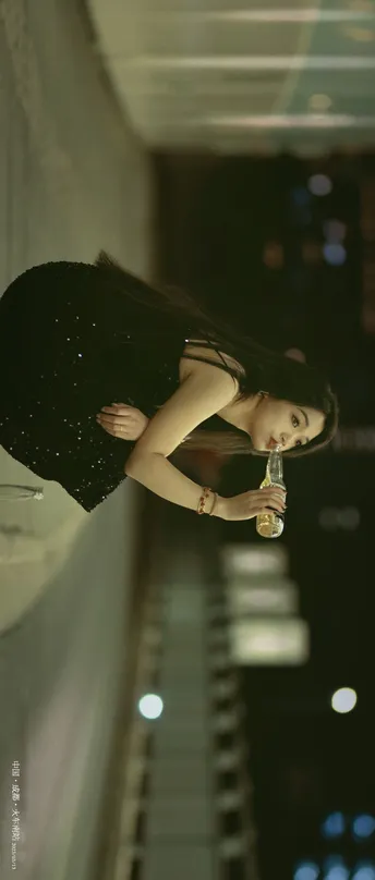 一位穿着黑色连衣裙的女士拿着一瓶水