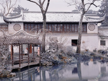 雪地上的建筑前有一个池塘和桥