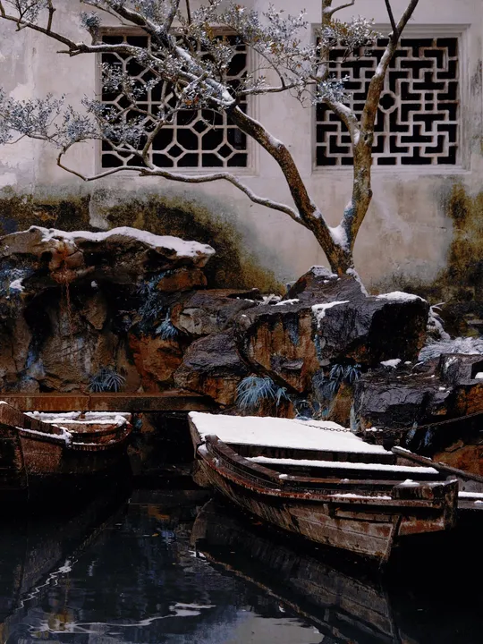 一艘小船停在结冰的池塘旁边 上面有些雪。