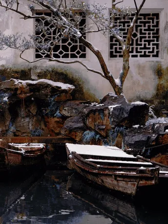 一艘小船停在结冰的池塘旁边 上面有些雪。