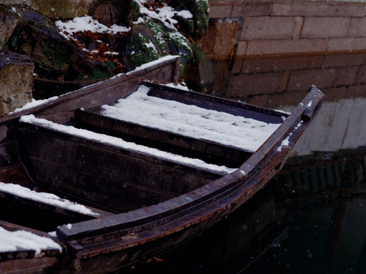 一艘被雪覆盖的老船停泊在水中