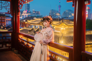 一位身着中国传统服装的年轻女子站在阳台俯瞰中国寺庙。