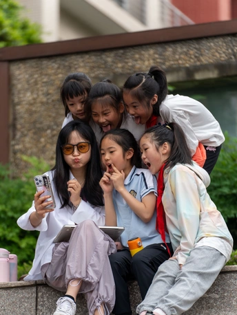 孩子们坐在墙上 用智能手机摆姿势拍照。