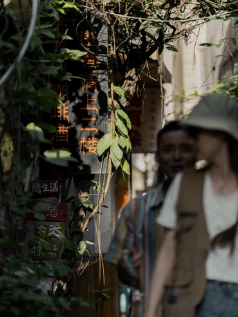 一位戴帽子的女士和一位戴帽子的男士正在沿着建筑旁边的人行道走