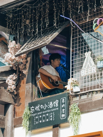 一个男人在挂着招牌的建筑物窗口弹吉他