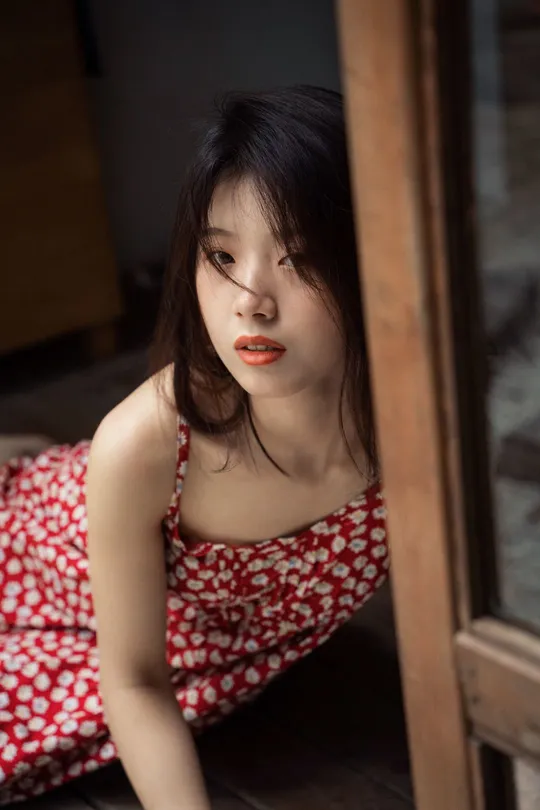 一个穿着红裙子的年轻女子坐在木地板上
