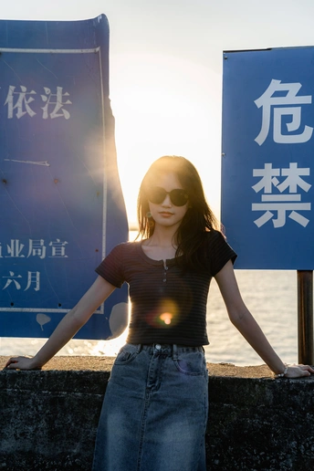 戴太阳镜的年轻女子站在水边的一个标志前