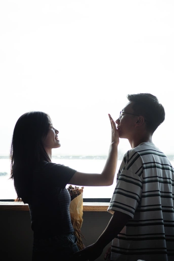 一个年轻男孩和一个年轻女孩站在窗前向外看 窗台上坐着一个 person。