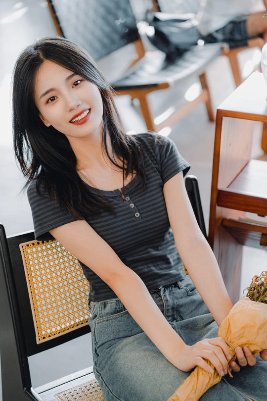 一个年轻女子坐在黑色椅子上的一张桌子旁