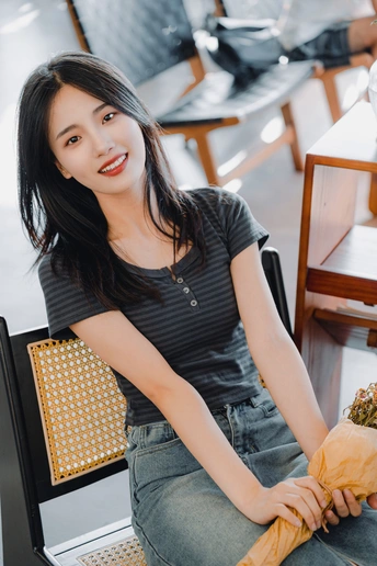 一个年轻女子坐在黑色椅子上的一张桌子旁