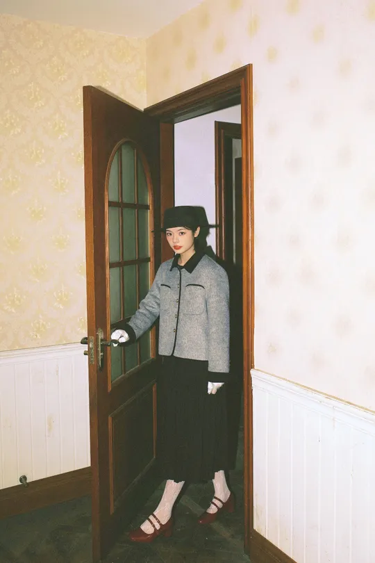 一位戴帽子的女人站在一个开着门的房间里