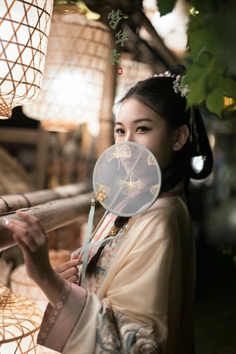 一位年轻女子穿着和服举起了一盏灯笼照在她脸上