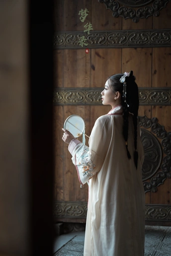 一位穿着传统裙子的年轻女孩站在一座寺庙的门前