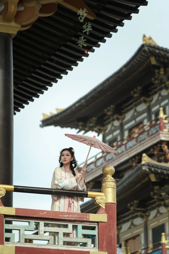 一位女士站在一栋建筑前拿着一把伞