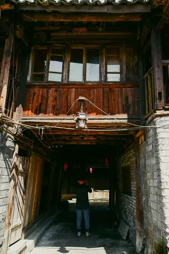 一个人站在一栋老木屋的入口处