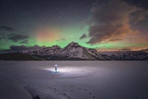 夜晚的冻结湖 背景是山脉 天空中出现了极光。
