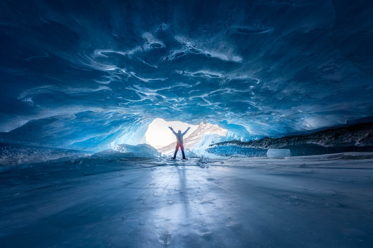 一个站在冰洞里的冰面上 双手伸向蓝色光的男子。