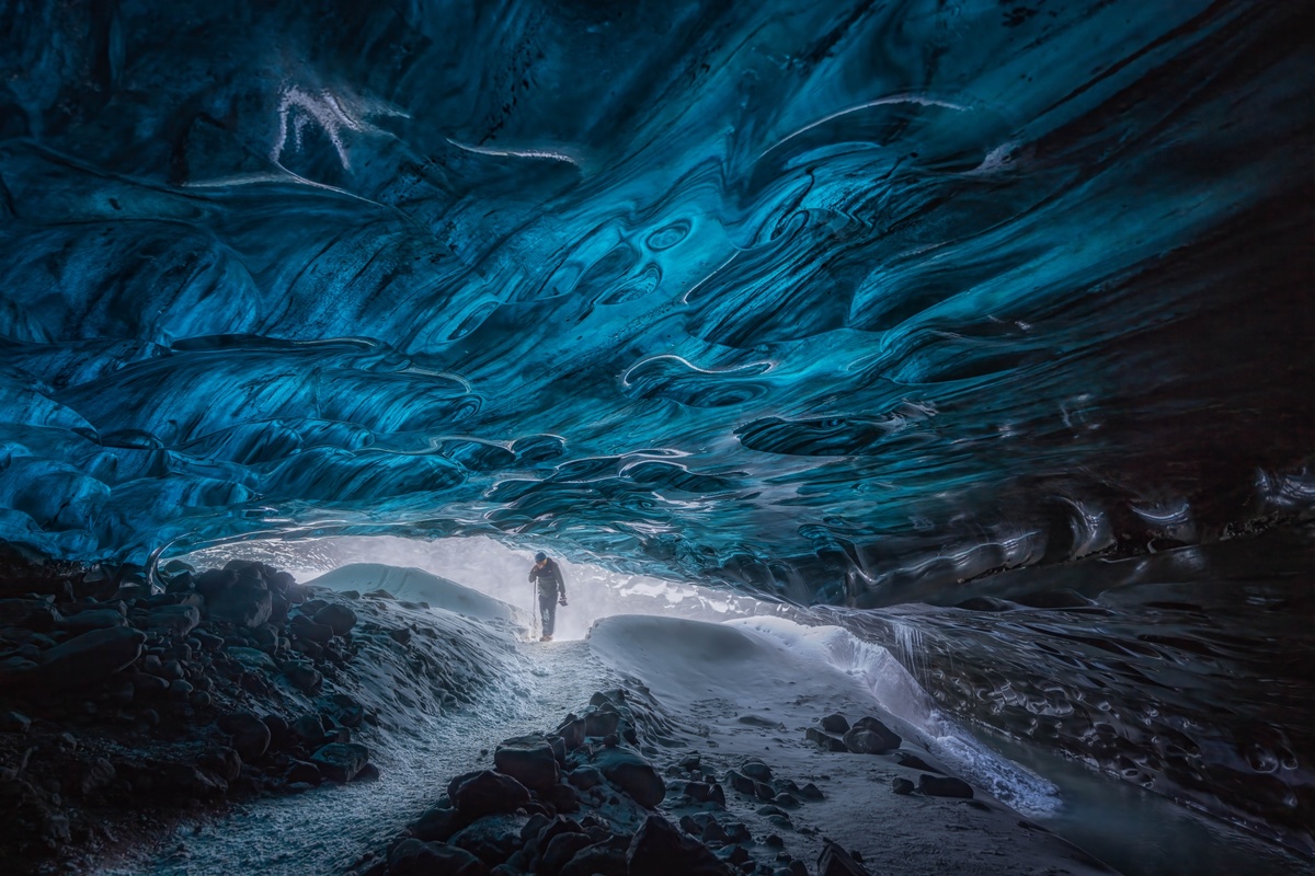 一个人走进了一个被蓝色光线照亮的巨大洞穴