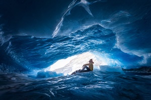 冰岛的一个洞穴里 一个男子和一个女子坐在蓝色的灯光下。