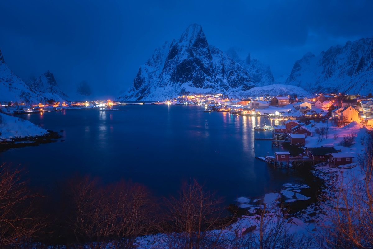 挪威洛弗特群岛的一个雪夜村庄的夜景 被山上的雪和背景中的山所照亮。