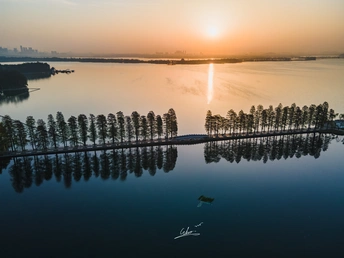 湖面或河流上的日落或日出 水中有船 远处有城市