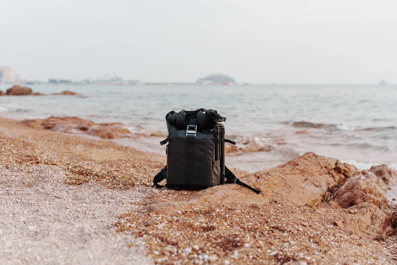 一个黑色的背包上有一个相机 位于海边的岩石上
