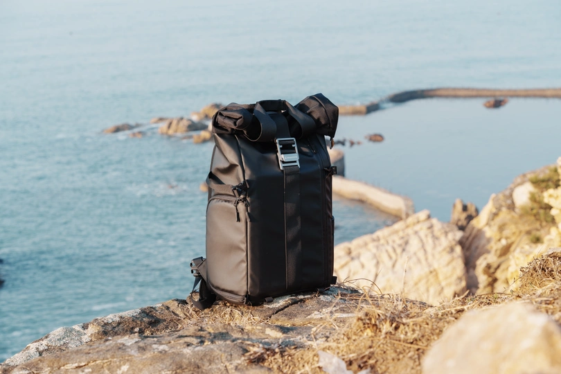 一个黑色的背包在俯瞰海洋和海景的岩石上