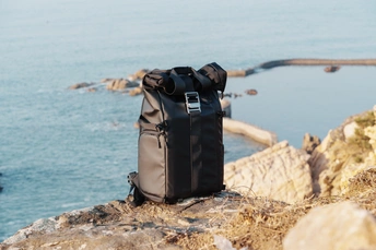 一个黑色的背包在俯瞰海洋和海景的岩石上