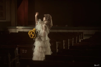 一位拿着向日葵花束的新娘 双手举过头顶 沿着教堂的通道走下去。