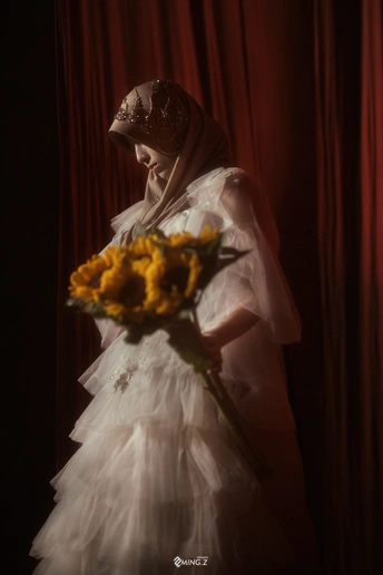 一位穿着白色连衣裙和面纱的年轻女子 手里拿着一束黄玫瑰花。