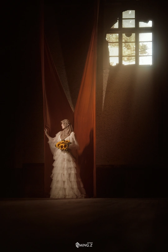 一个穿着白色婚纱的女人站在一个黑暗的房间里 有红色的窗帘。