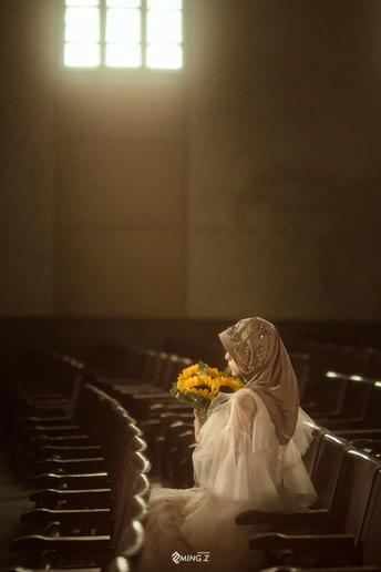 一个抱着黄色花朵的女人走过一个教堂空荡荡的走道