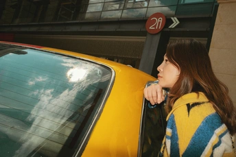 一位年轻女子在黄色的出租车上 车停在交通标志处 正在车窗外伸头。