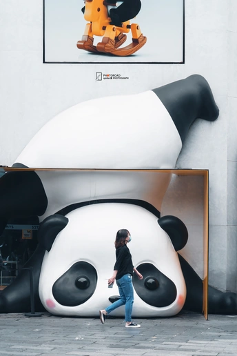 一名妇女走过一张大熊猫的大幅照片