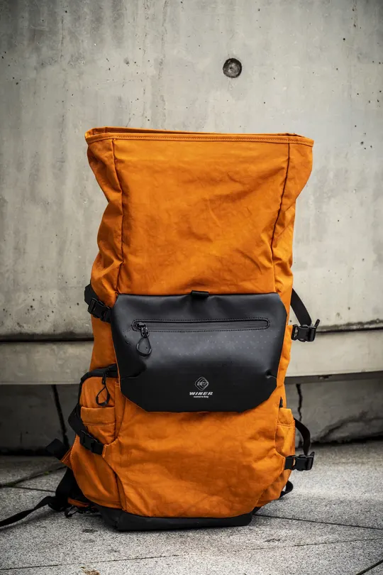 橙色背包靠在混凝土墙上